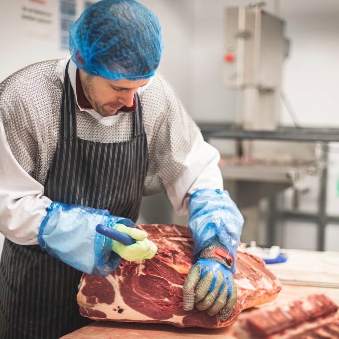 A butcher from Riverford cutting a joint of beef